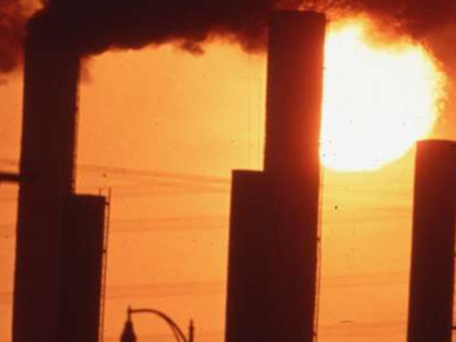 Several tall smokestacks emitting thick black smoke.