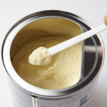 Representative Image. A hand holding a white plastic scoop filled with powdered formula. Photo Source - 국립국어원 (CC BY-SA 2.0 KR)