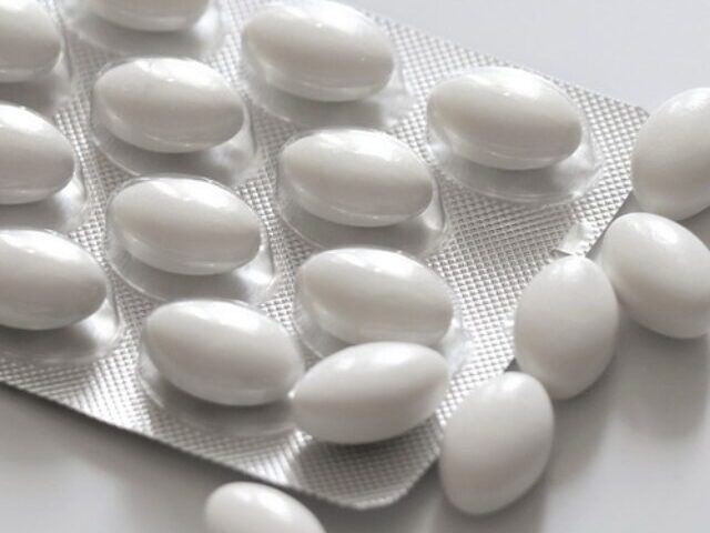 A blister pack containing white, oval-shaped pills, with some pills scattered on a white surface. Photo Source: Needpix.com- Olga1205 (pixabay.com)