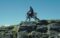 A person riding what appears to be a futuristic robotic horse or a mechanical quadruped on a rocky hilltop under a clear blue sky. Photo Source: Kawasaki Group Channel (YouTube)
