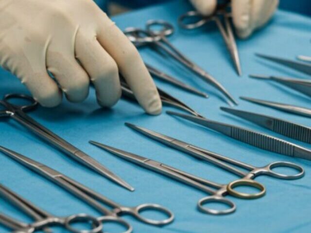 Representative Image: A medical professional wearing a blue surgical gown and sterile gloves is organizing surgical instruments on a sterile blue drape. Photo Source: AI Generated