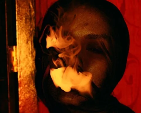 Woman wearing see- through Fabric on Face and smoking Photo Source-PEXELS- Ruslan Rozanov