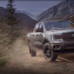 A Ford pickup truck driving on a rugged dirt trail through a scenic mountainous landscape. Photo Source: Ford