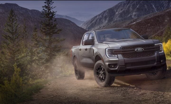 A Ford pickup truck driving on a rugged dirt trail through a scenic mountainous landscape. Photo Source: Ford