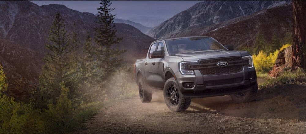 A Ford pickup truck driving on a rugged dirt trail through a scenic mountainous landscape. Photo Source: Ford