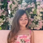 A nine year old Leah smiling against a beach background to support fundraising for her shark‑attack recovery.