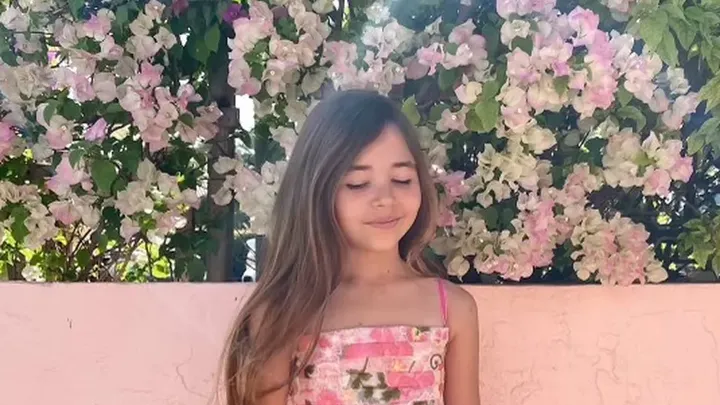 A nine year old Leah smiling against a beach background to support fundraising for her shark‑attack recovery.