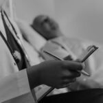 Doctor Holding a Medical Chart Sitting beside a Patient