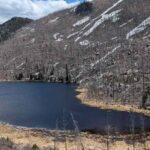 A high-altitude lake surrounded by scorched and barren trees