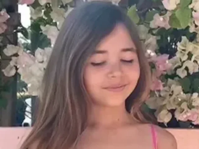 A nine year old Leah smiling against a beach background to support fundraising for her shark‑attack recovery.