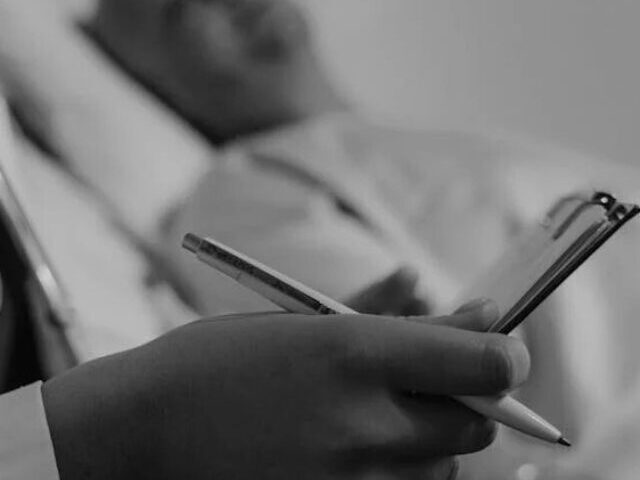 Doctor Holding a Medical Chart Sitting beside a Patient