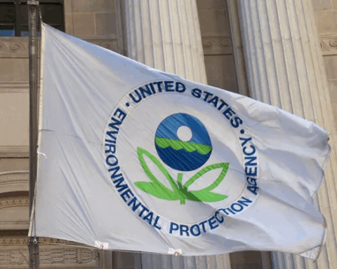 EPA flag featuring the agency’s seal—a stylized two-leaved flower beneath a sphere symbolizing sky, water, and earth—flying outside a government building. Photo Source: Paul A. Fagan (CC BY 2.0)