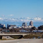 Alt Text: Downtown Fresno skyline with snow-capped Sierra Nevada mountains under a clear blue sky.