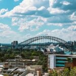 View over Potts Point rooftops to the Sydney Harbour Bridge and Opera House under a partly cloudy sky.