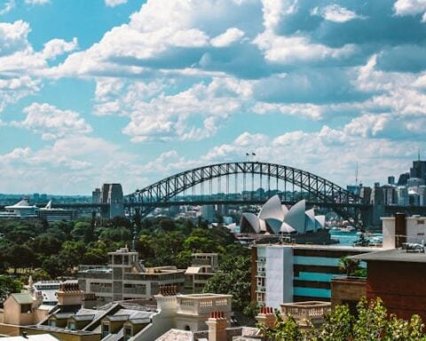 View over Potts Point rooftops to the Sydney Harbour Bridge and Opera House under a partly cloudy sky.