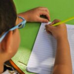 Close-Up Shot of a Kid Writing on Notebook Using a Pencil
