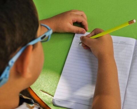 Close-Up Shot of a Kid Writing on Notebook Using a Pencil