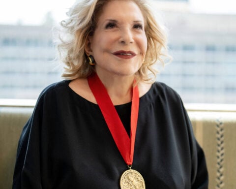 Portrait of Wallis Annenberg wearing her National Humanities Medal, smiling against a blurred urban backdrop.