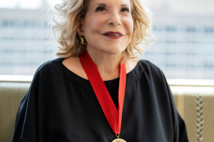 Portrait of Wallis Annenberg wearing her National Humanities Medal, smiling against a blurred urban backdrop.