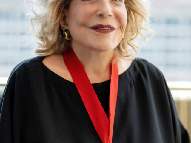 Portrait of Wallis Annenberg wearing her National Humanities Medal, smiling against a blurred urban backdrop.
