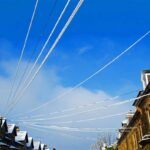 Snow-covered power lines above a row of brick houses, illustrating the network infrastructure underpinning every home’s energy bill.