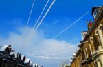 Snow-covered power lines above a row of brick houses, illustrating the network infrastructure underpinning every home’s energy bill.