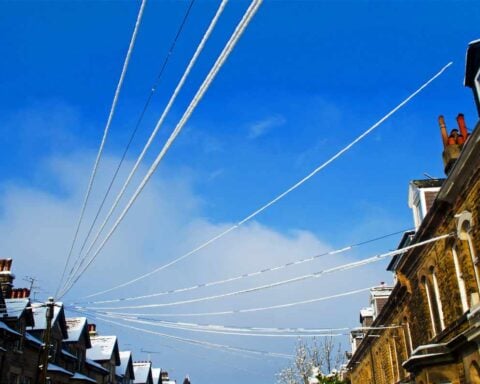 Snow-covered power lines above a row of brick houses, illustrating the network infrastructure underpinning every home’s energy bill.