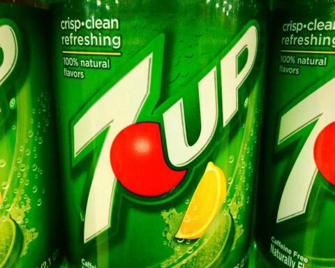 Two green 7Up soda cans showing the tropical flavor variant branding with crisp clean refreshing text and 100% natural flavors labeling