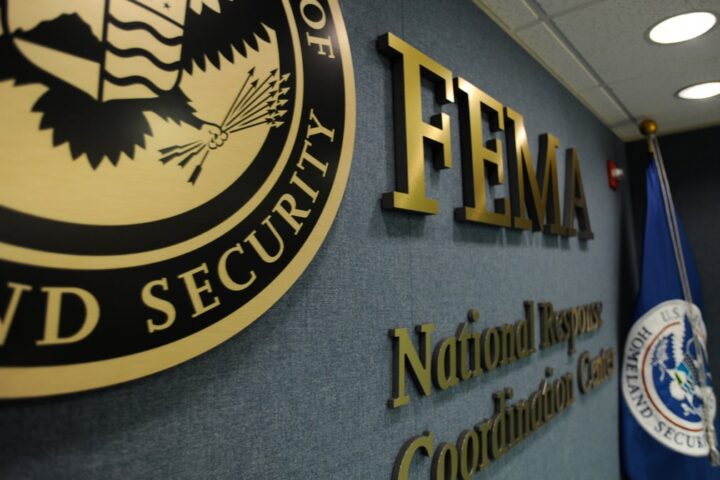 FEMA National Response and Coordination Center interior with FEMA logo, DHS seal, and flag — central hub for U.S. disaster management operations.