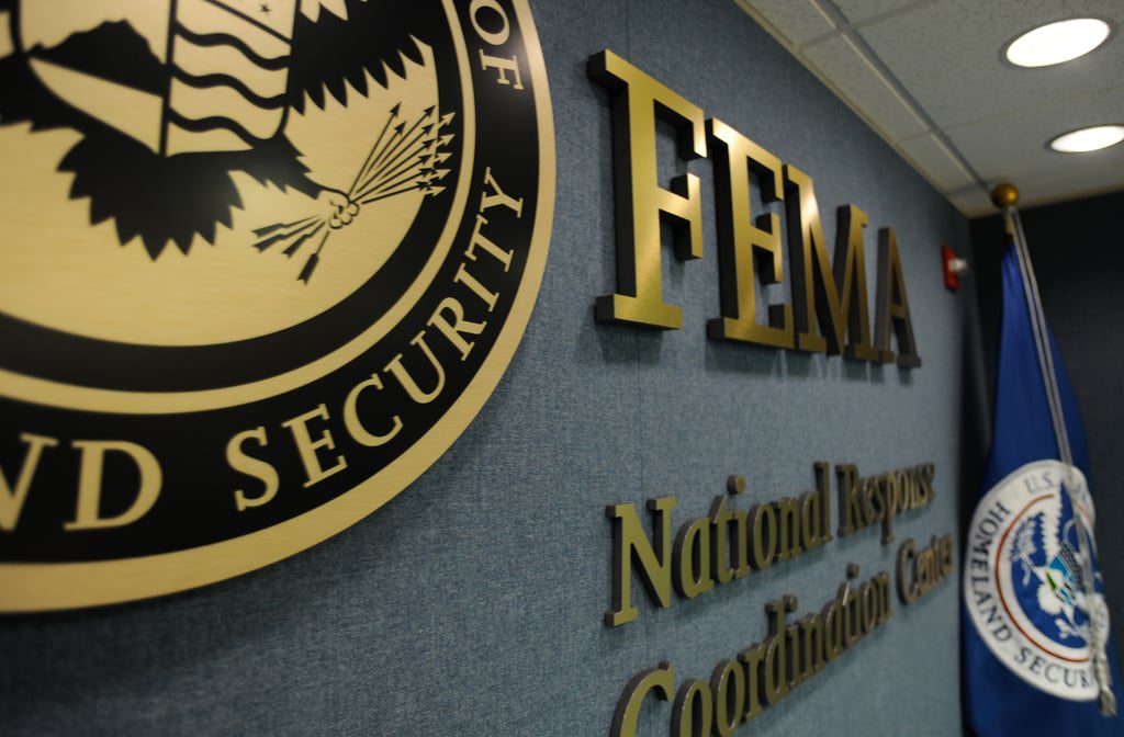 FEMA National Response and Coordination Center interior with FEMA logo, DHS seal, and flag — central hub for U.S. disaster management operations.