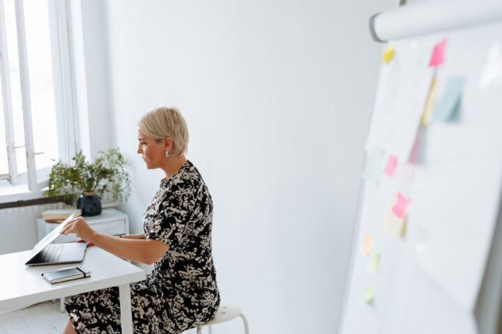 Woman in Black and White Floral Dress Sitting on White Chair