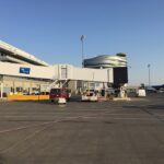 Modern exterior view of Edmonton International Airport terminal with jet bridges, parked aircraft including WestJet, and ground service vehicles.