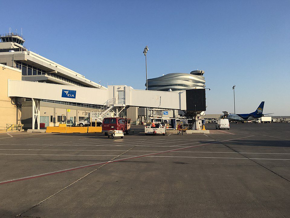 Modern exterior view of Edmonton International Airport terminal with jet bridges, parked aircraft including WestJet, and ground service vehicles.