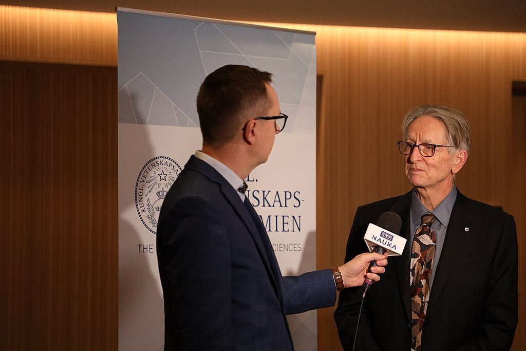 Geoffrey Hinton speaking at a Nobel Prize press conference, discussing unconventional AI safety approaches