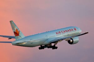 Air Canada Boeing 777-200LR aircraft taking off from Toronto Pearson Airport with sunset sky background.