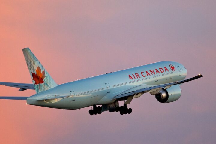 Air Canada Boeing 777-200LR aircraft taking off from Toronto Pearson Airport with sunset sky background.