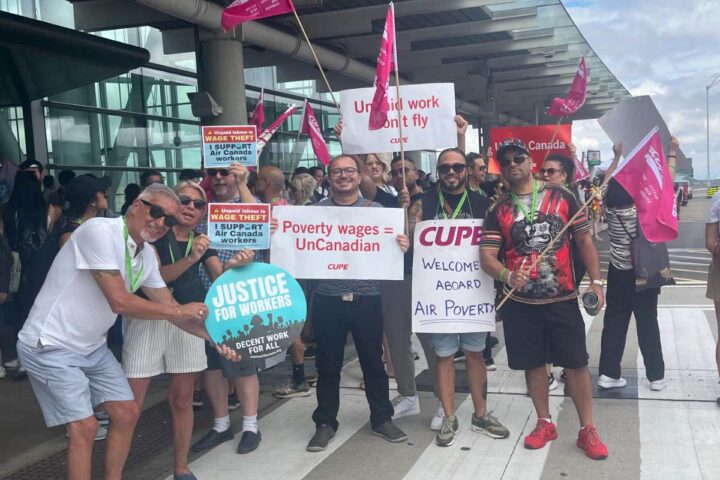 Air Canada flight attendants and supporters protest wage theft and unpaid pre-boarding duties outside an airport terminal, holding CUPE and Justice for Workers signs.