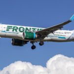 Frontier Airlines Airbus A320neo (N389FR) on final approach at Baltimore–Washington International, side view with animal-tail livery against a clear blue sky.