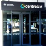 Entrance to a Centrelink service centre with glass doors and signage, representing Australian Government social security services.