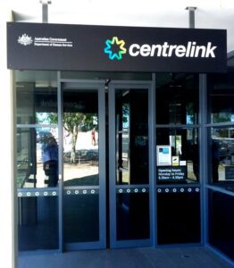 Entrance to a Centrelink service centre with glass doors and signage, representing Australian Government social security services.