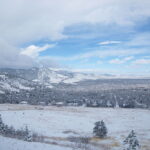 Snow-covered Boulder landscape with mountains and trees under a partly cloudy sky