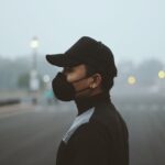 Side profile of a person wearing a protective mask standing outdoors in heavy haze.
