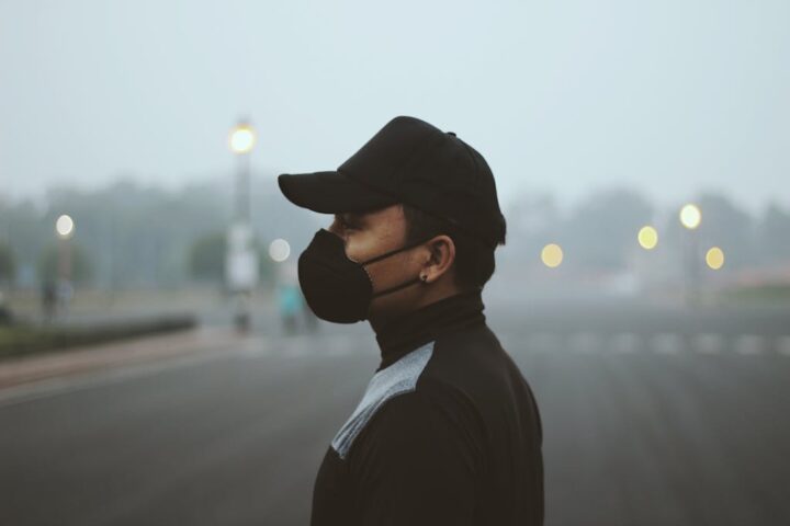 Side profile of a person wearing a protective mask standing outdoors in heavy haze.