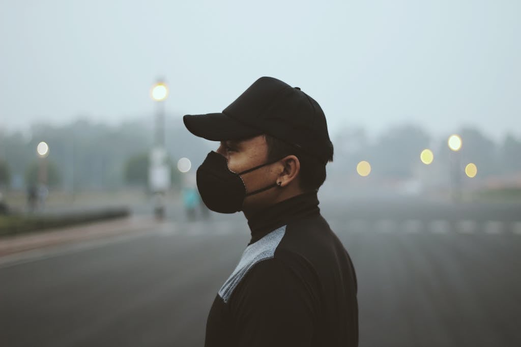 Side profile of a person wearing a protective mask standing outdoors in heavy haze.