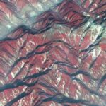 Satellite view of mountainous terrain in Sichuan showing ridges and valleys with color-coded elevation and vegetation patterns, used in research on post-earthquake river sediment dynamics