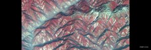 Satellite view of mountainous terrain in Sichuan showing ridges and valleys with color-coded elevation and vegetation patterns, used in research on post-earthquake river sediment dynamics