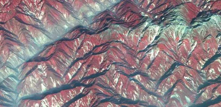 Satellite view of mountainous terrain in Sichuan showing ridges and valleys with color-coded elevation and vegetation patterns, used in research on post-earthquake river sediment dynamics