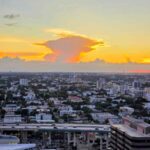 Smoke haze from Everglades wildfires drifting over a Broward County highway under a gray sky.