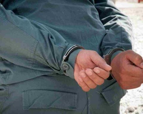 A person’s hands secured in metal handcuffs behind their back.