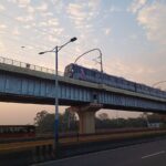 Pune Metro train running on the elevated viaduct between Bopodi and Dapodi during sunset.